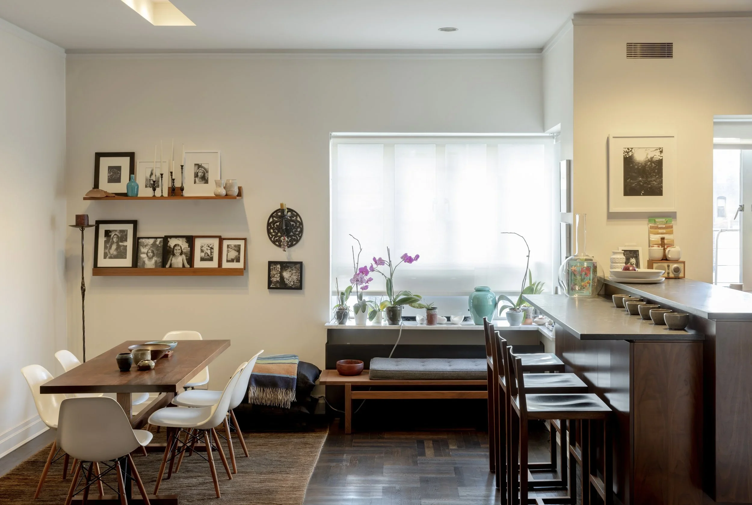 A modern, minimalist kitchen with light grey cabinets, white countertops, stainless steel sink and gas stovetop.
