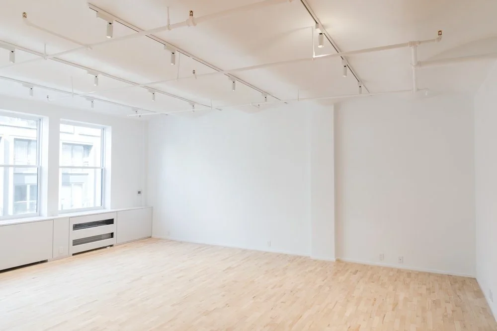 Full shot of light grey wall-mounted storage unit. It has four open shelves at the top, a fluorescent light bar installed below the top shelf, and cabinets and drawers at the bottom. The drawers are open.